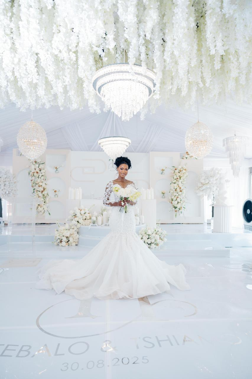 Bride beneath a ceiling of white florals and crystal chandeliers