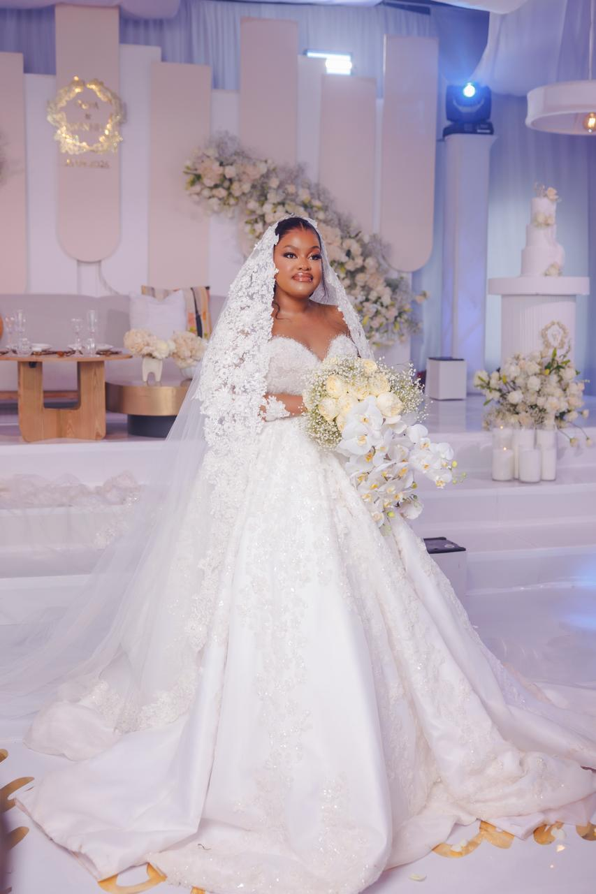 Bride holding orchids in an all-white ceremony setting