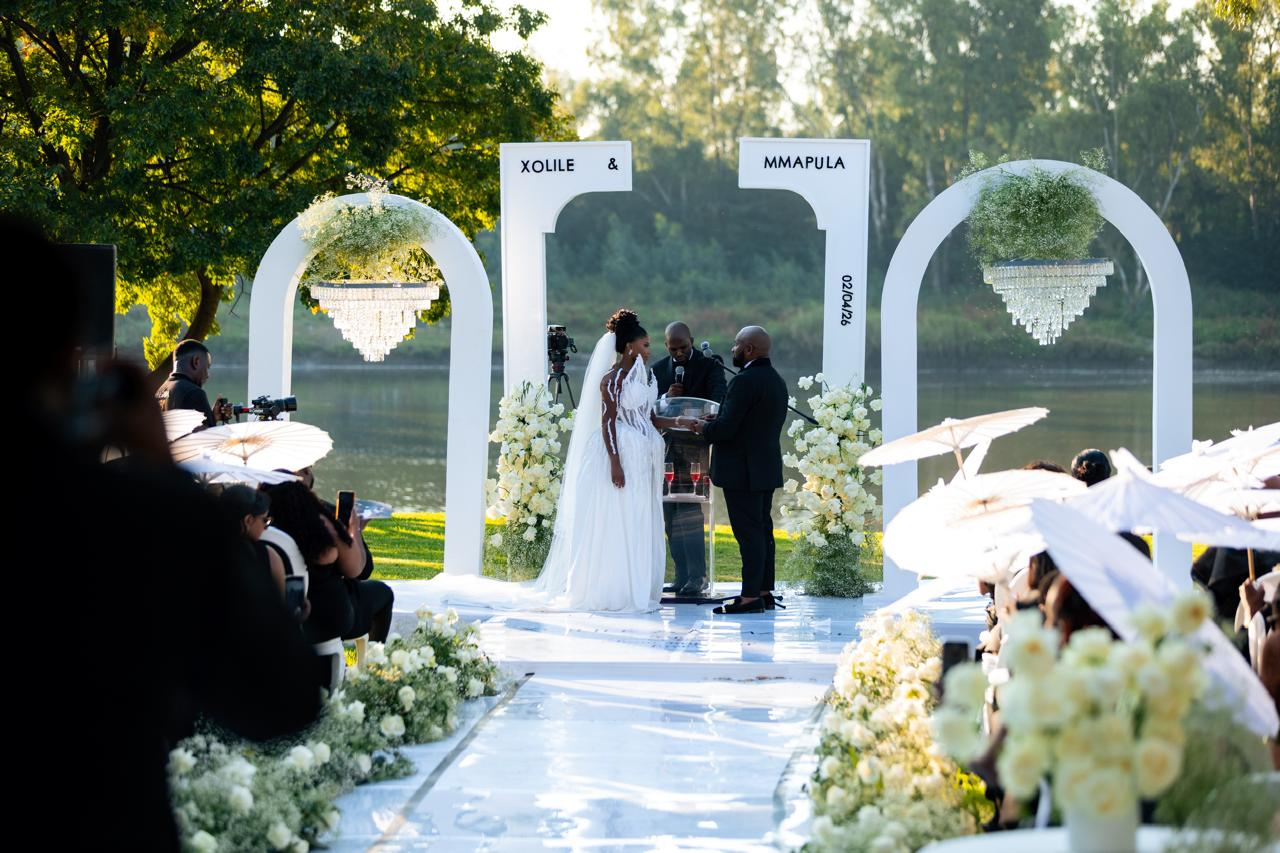 Outdoor lakeside wedding ceremony framed by sculptural white arches