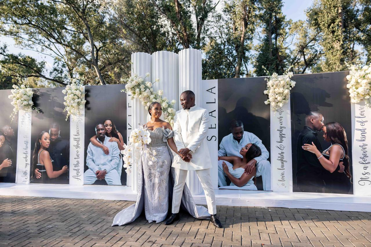 Couple posing in front of a black and white portrait wall display