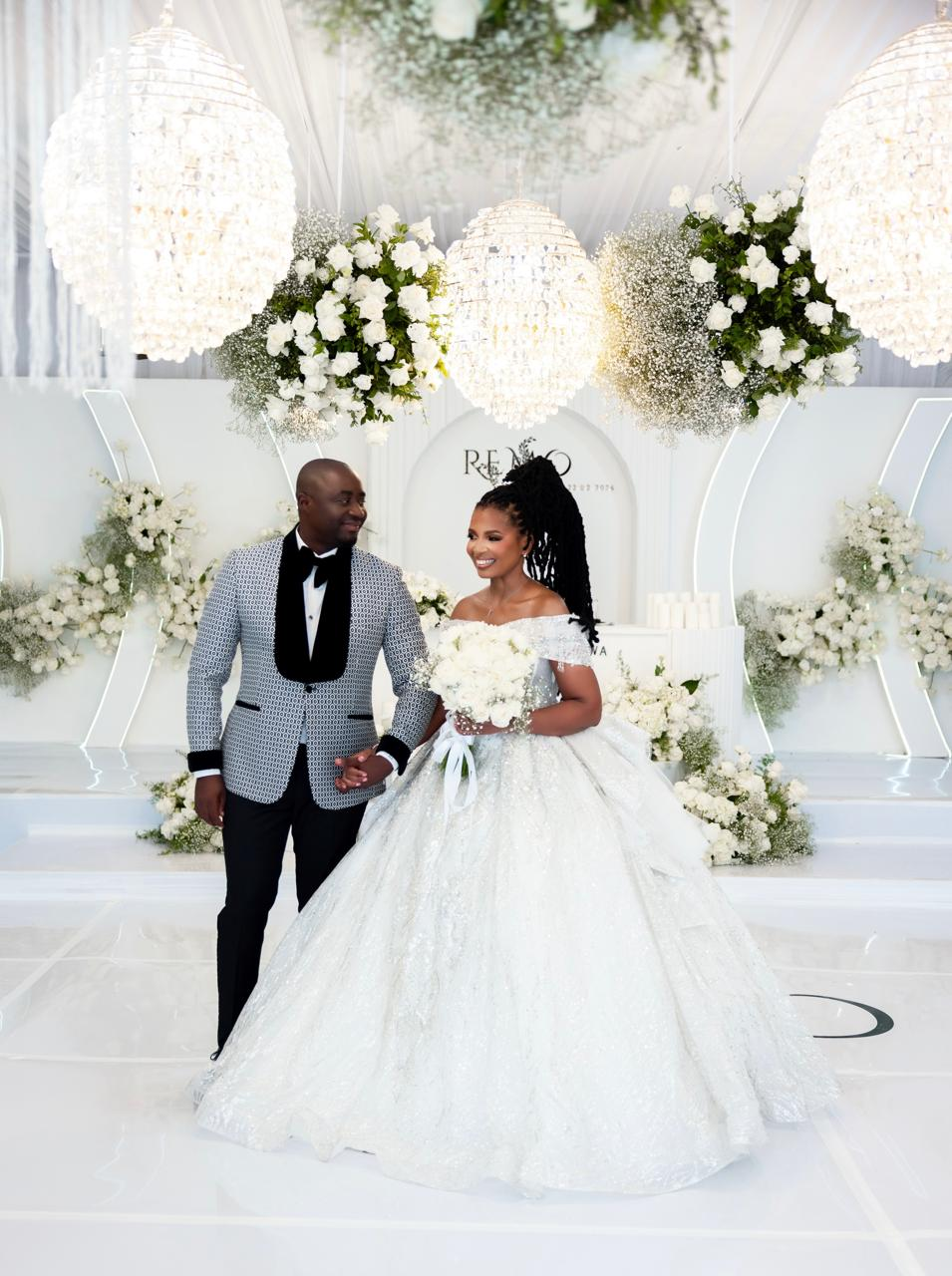 Couple walking together in a white floral reception space