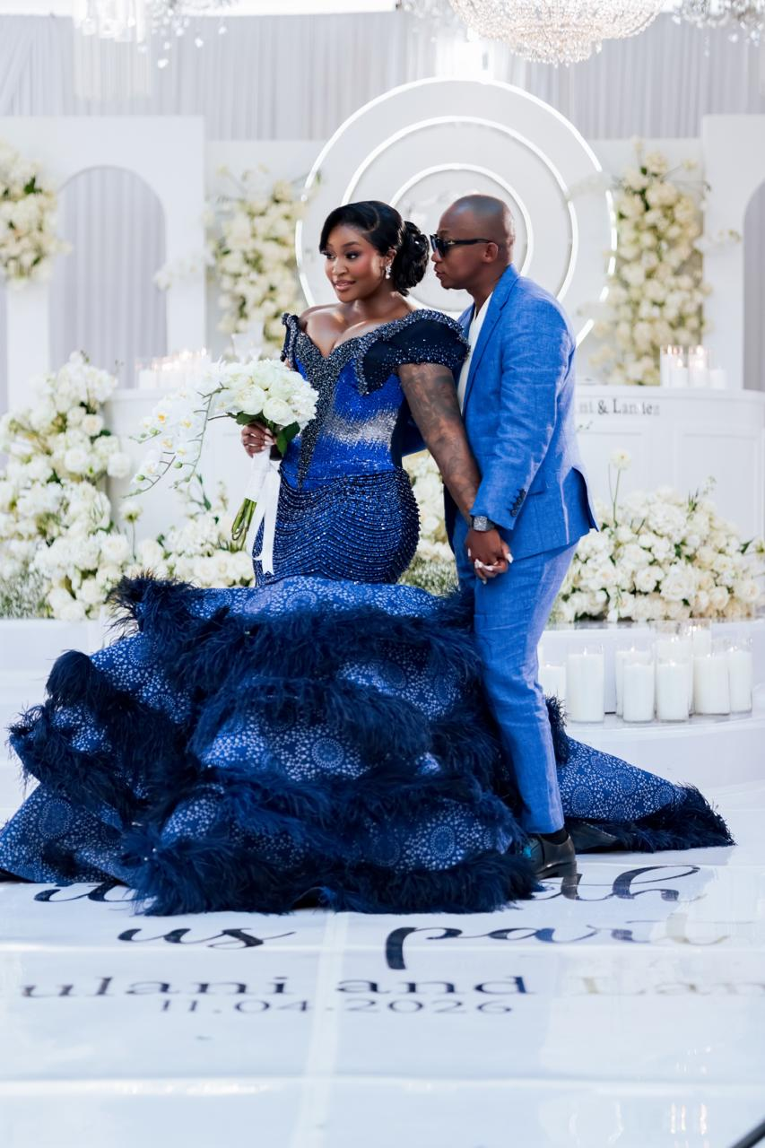 Couple in royal blue formalwear at a chandelier-lit wedding reception